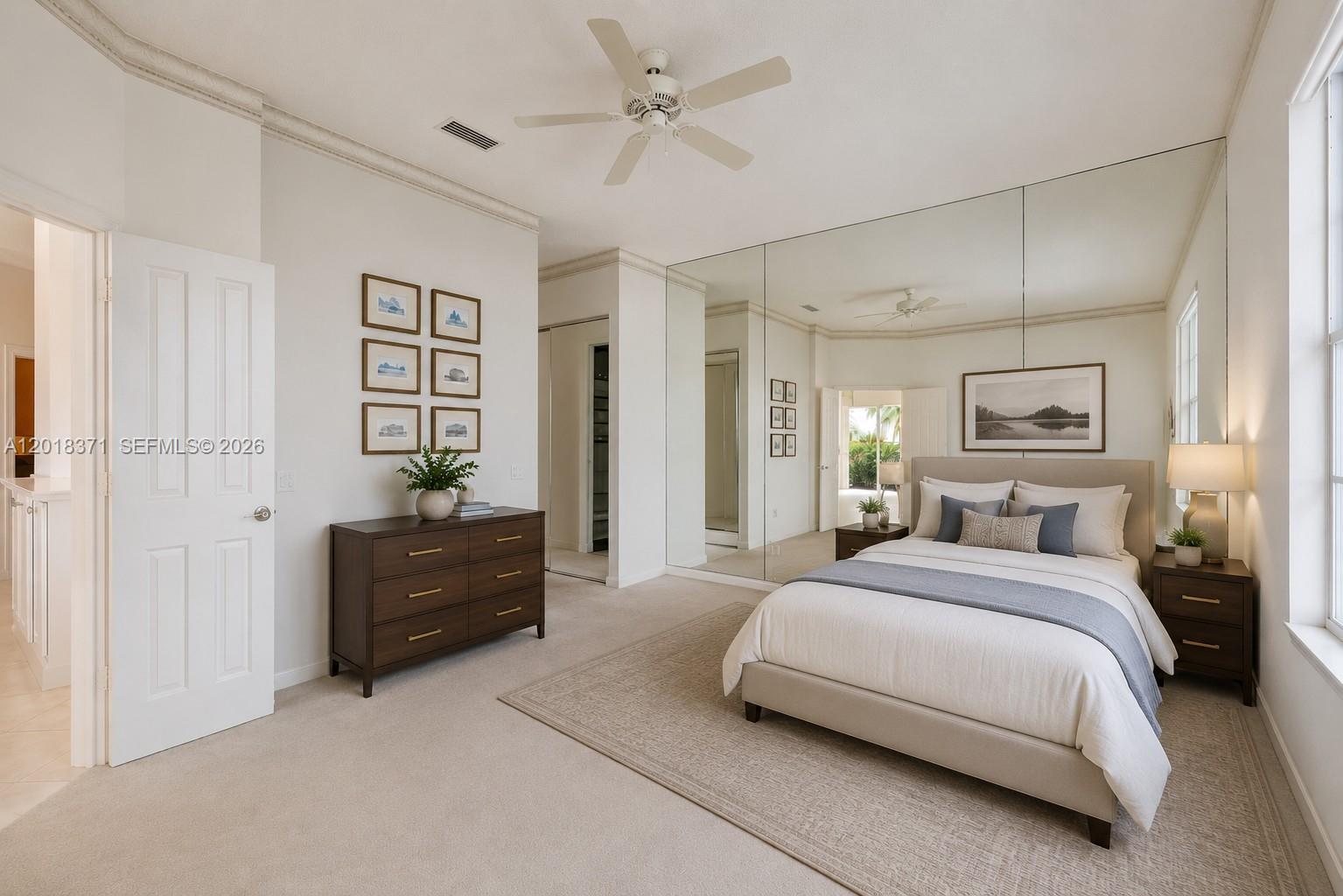 A bedroom features a bed, mirrored wall, dresser, and neutral carpeted flooring — 7968 SE Double Tree Dr, Hobe Sound FL 33455, HOBE SOUND, FL