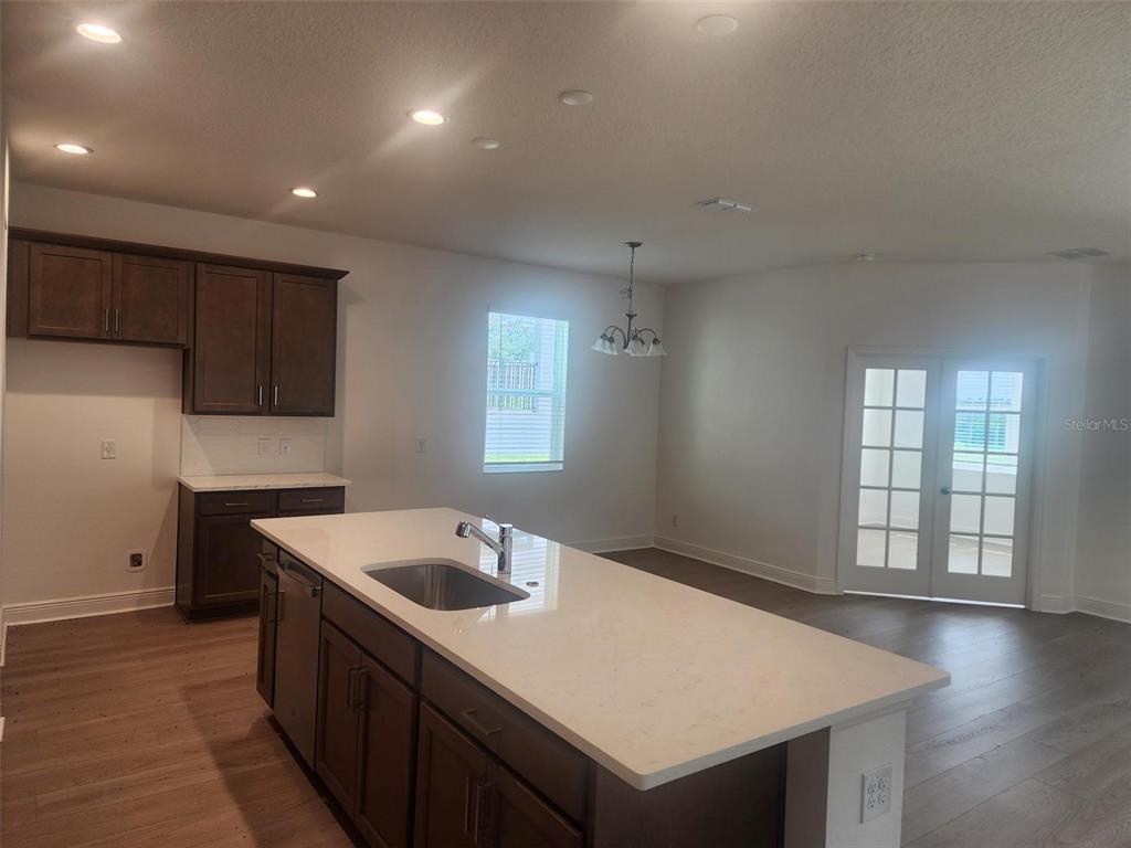 A kitchen with dark wood cabinets, a white quartz island, and a dining area — 7501 CATANIA LOOP, CLERMONT, FL