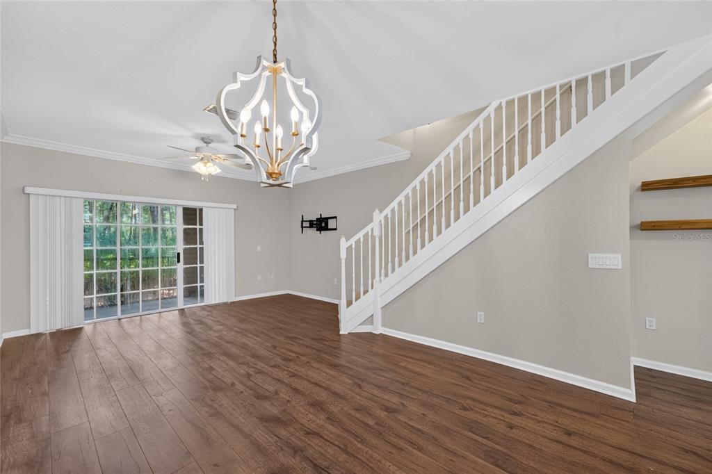 A living room with wood-look flooring, a staircase, a ceiling fan, and a pass-through window — 5008 NW 44TH LANE UNIT 102, GAINESVILLE, FL
