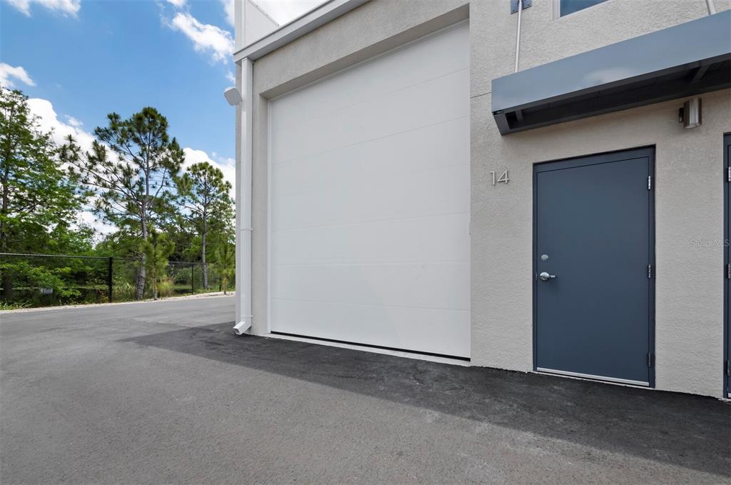 An exterior view of a building unit featuring a white garage door and gray door — 829 57TH STREET E UNIT 14, BRADENTON, FL