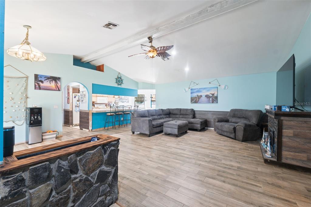 A living room with light blue walls, wood-look tile flooring, a stone fireplace, and furniture — 18160 SPANGLER AVENUE, BROOKSVILLE, FL