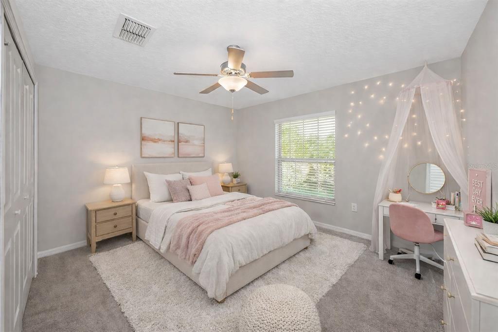 A bedroom features a bed with pink accents, a desk with a canopy, and gray carpet — 16612 CARLTON POND STREET, WIMAUMA, FL