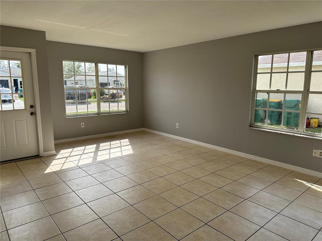 An empty room with light-colored tile flooring, gray walls, and two windows — 425 RICOLD TERRACE, PORT CHARLOTTE, FL