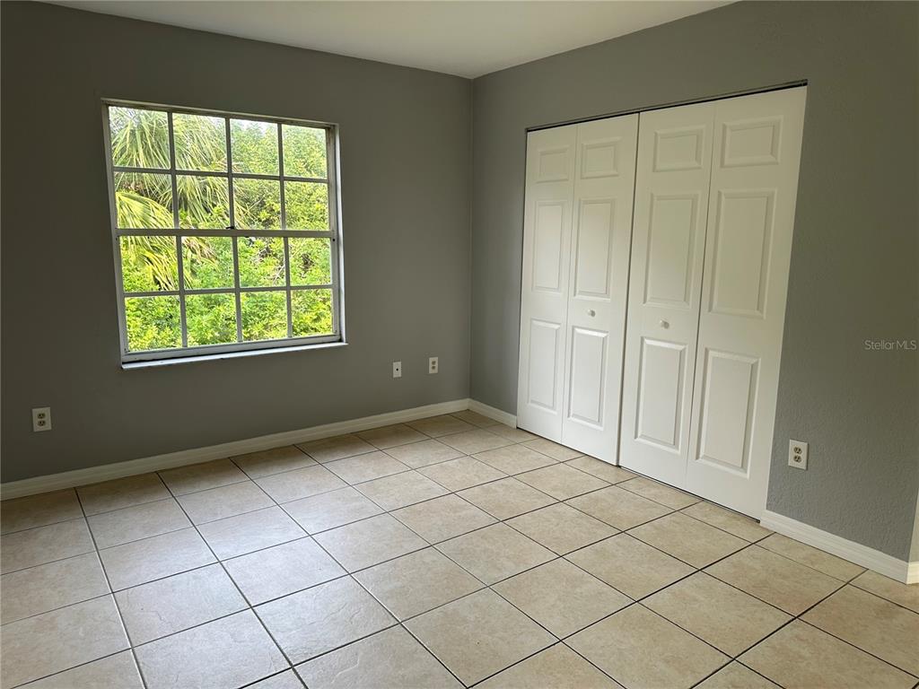 An empty bedroom features gray walls, tile flooring, a window, and white bifold closet doors — 425 RICOLD TERRACE, PORT CHARLOTTE, FL