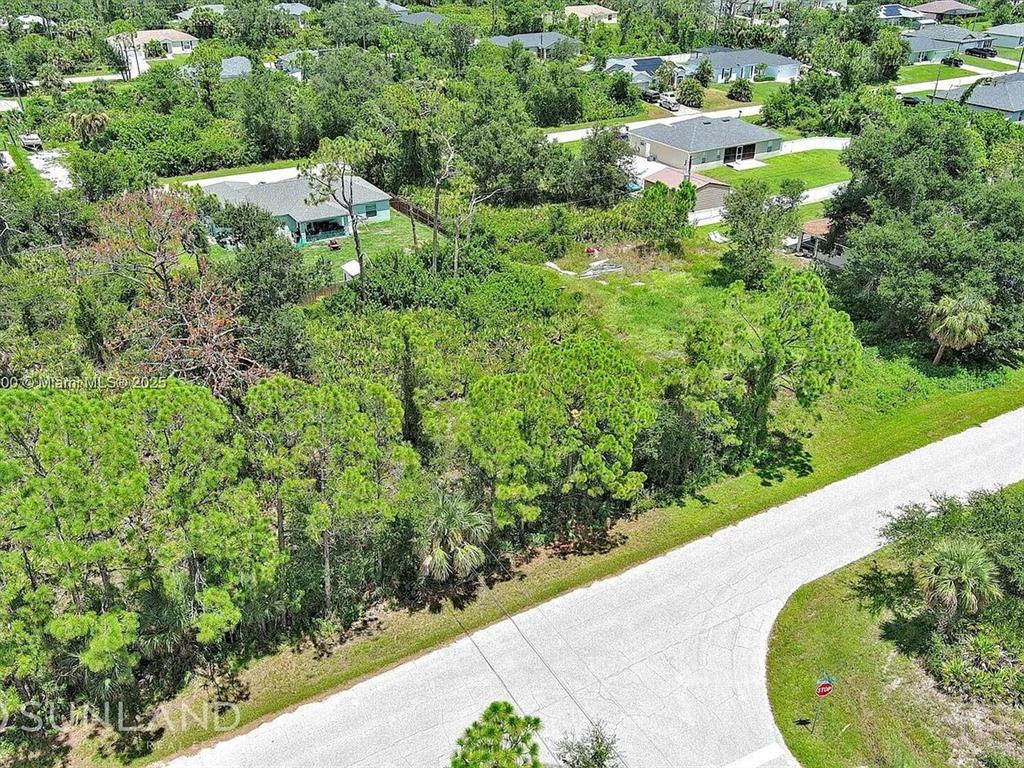 An aerial view shows a vacant, tree-covered lot situated between two residential houses — 11944 BROOKSIDE AVENUE, PORT CHARLOTTE, FL