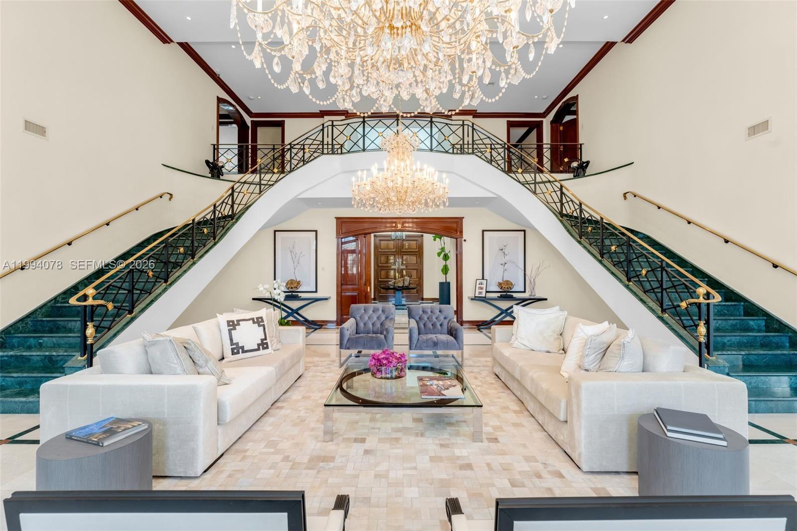 A grand foyer features dual staircases, two crystal chandeliers, and a formal seating area — 585 Arvida Pkwy, Coral Gables FL 33156, CORAL GABLES, FL