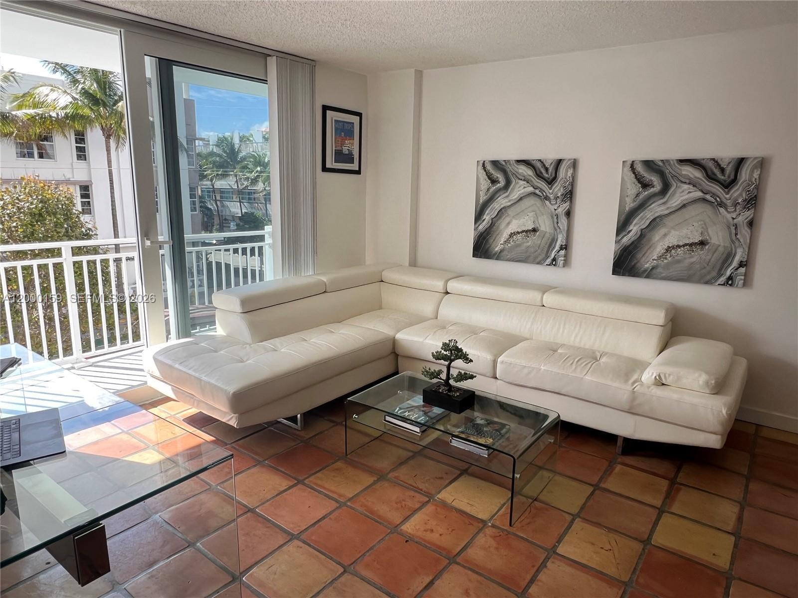 A living room features a white sectional sofa, glass coffee table, and terracotta tile flooring — 345 Ocean Dr # 303, Miami Beach FL 33139, MIAMI BEACH, FL