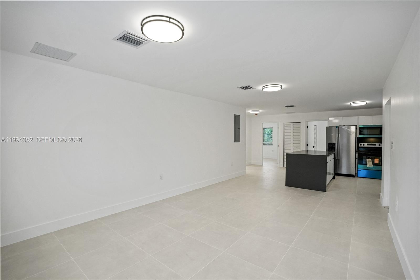 An open-concept room features white walls, light tile flooring, and a modern kitchen area — 5823 NW 30th ave # 5823, Miami FL 33142, MIAMI, FL
