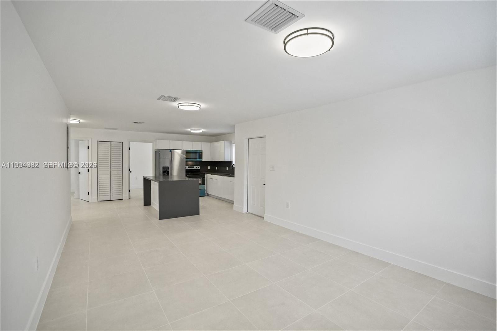 This open-concept kitchen and living area features white walls, light tile flooring, and cabinetry — 5823 NW 30th ave # 5823, Miami FL 33142, MIAMI, FL