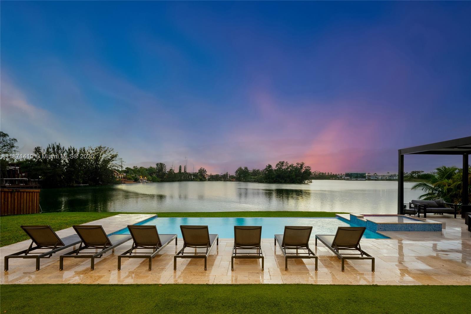 A swimming pool with lounge chairs overlooks a lake under a sunset sky — 5420 SW 72nd Ave, Miami FL 33155, MIAMI, FL