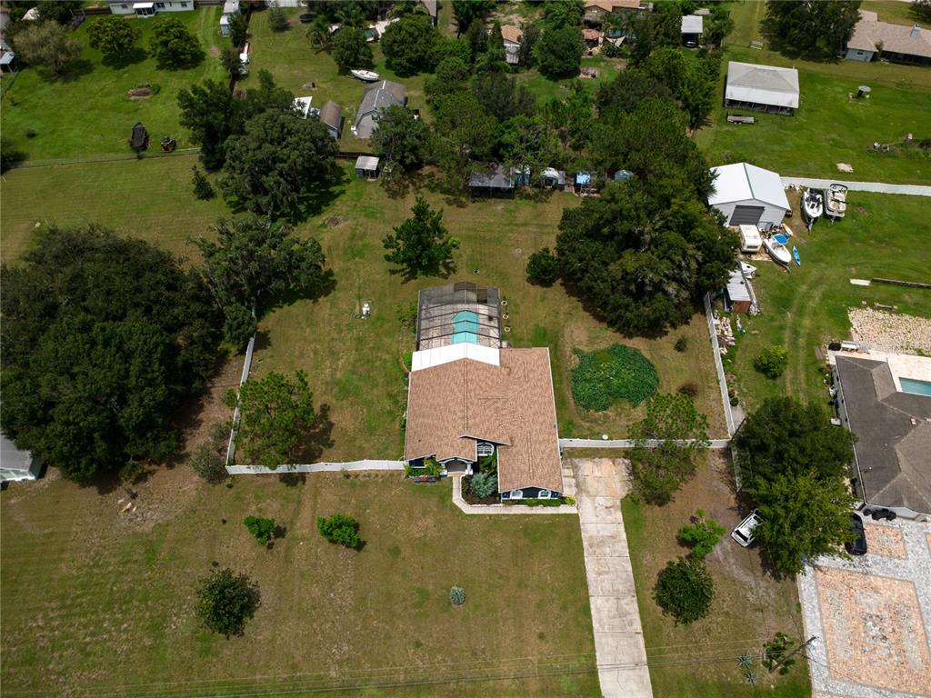 An aerial view shows a house with a pool enclosure on a large grassy lot — 31439 STIRRUP LANE, WESLEY CHAPEL, FL