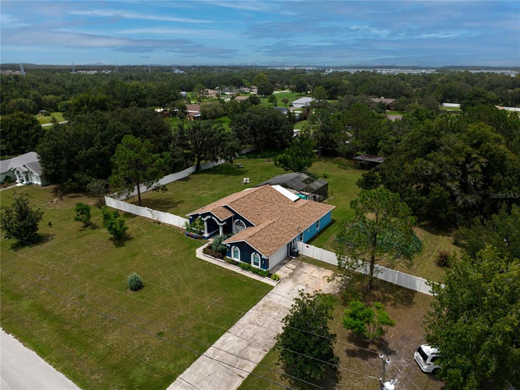 An aerial view shows a single-story house with a brown roof and a fenced backyard — 31439 STIRRUP LANE, WESLEY CHAPEL, FL
