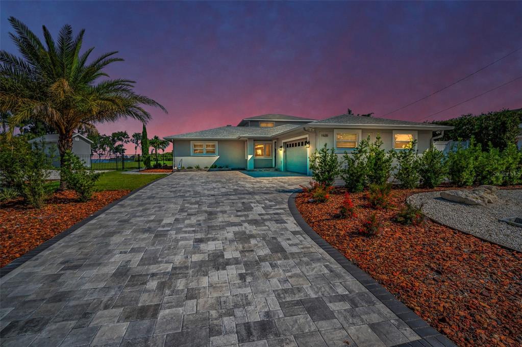 A single-story house with a paved driveway, palm tree, and landscaping at sunset — 1620 SEA BREEZE DRIVE, TARPON SPRINGS, FL