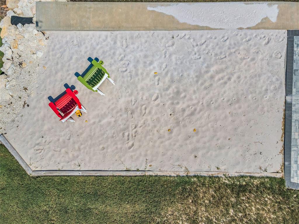 An aerial view shows two colorful Adirondack chairs sitting in a rectangular backyard sand pit — 1620 SEA BREEZE DRIVE, TARPON SPRINGS, FL