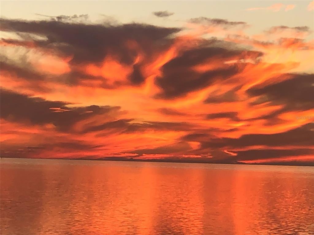 A vibrant orange and red sunset reflects over a calm body of water — 1620 SEA BREEZE DRIVE, TARPON SPRINGS, FL