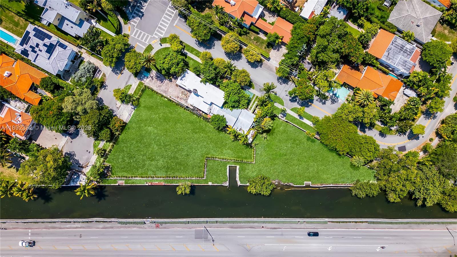 An aerial view shows a large, vacant grassy lot situated along a canal — 1800 Michigan Ave, Miami Beach FL 33139, MIAMI BEACH, FL