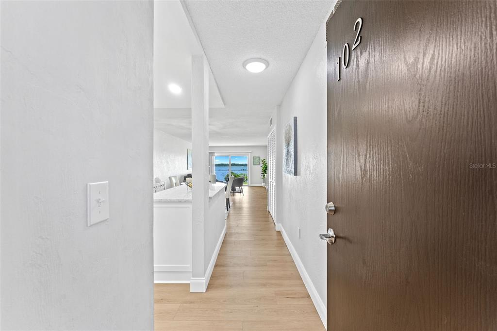 A view from a doorway looking down a hallway toward a bright living area — 3606 S PENINSULA DRIVE UNIT 102, PORT ORANGE, FL