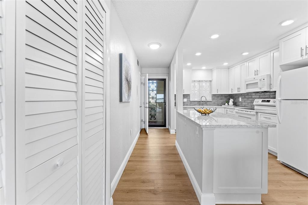 A bright kitchen features white cabinetry, granite countertops, and light wood-look flooring — 3606 S PENINSULA DRIVE UNIT 102, PORT ORANGE, FL