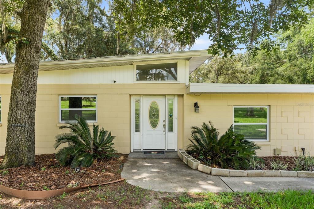 A single-story house with a light yellow block exterior, white trim, and a front entrance — 10907 SW 24TH AVENUE, GAINESVILLE, FL