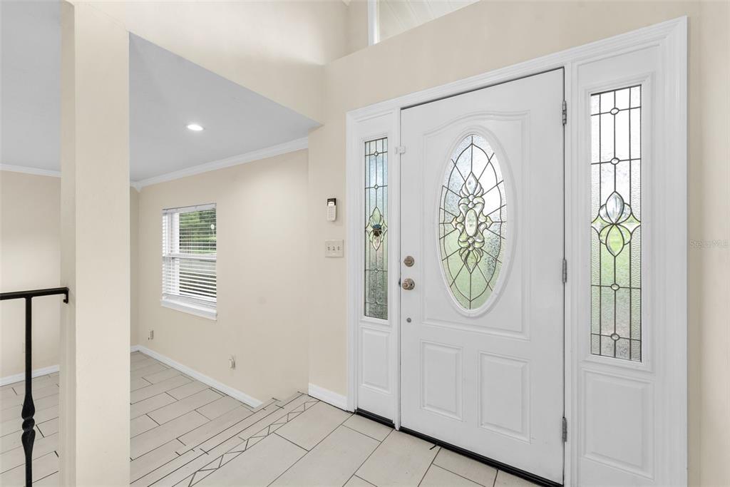 A bright entryway features a white front door with a decorative glass oval insert — 10907 SW 24TH AVENUE, GAINESVILLE, FL