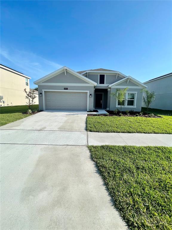 A single-story house with a light gray exterior, a two-car garage, and a concrete driveway — 4491 TAHOE CIRCLE, CLERMONT, FL