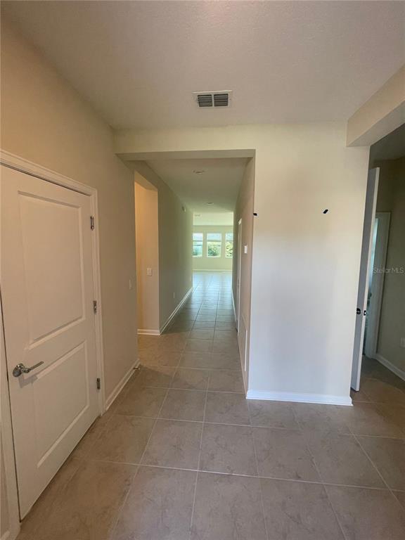 A tiled hallway leads from a foyer toward a bright, open living area with windows — 4491 TAHOE CIRCLE, CLERMONT, FL