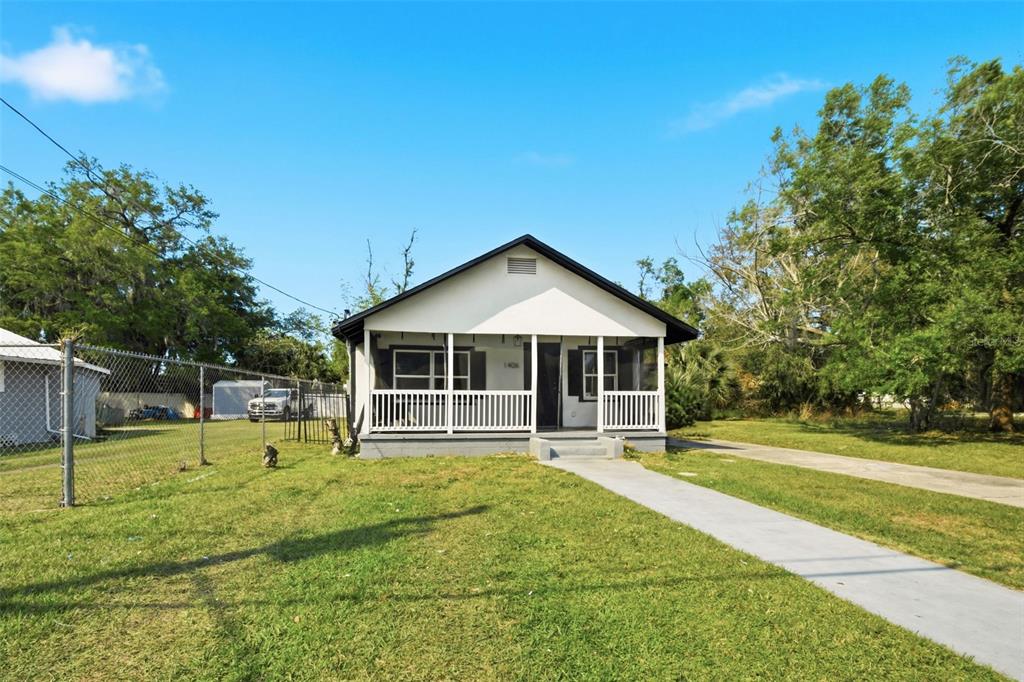 A single-story house with a white exterior, a front porch, and a concrete walkway — 1406 W 15TH STREET, SANFORD, FL