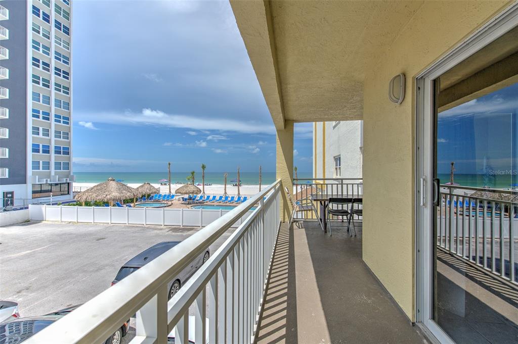 A balcony with a metal railing overlooks a parking lot, swimming pool, and the ocean — 17450 GULF BOULEVARD UNIT 103, REDINGTON SHORES, FL