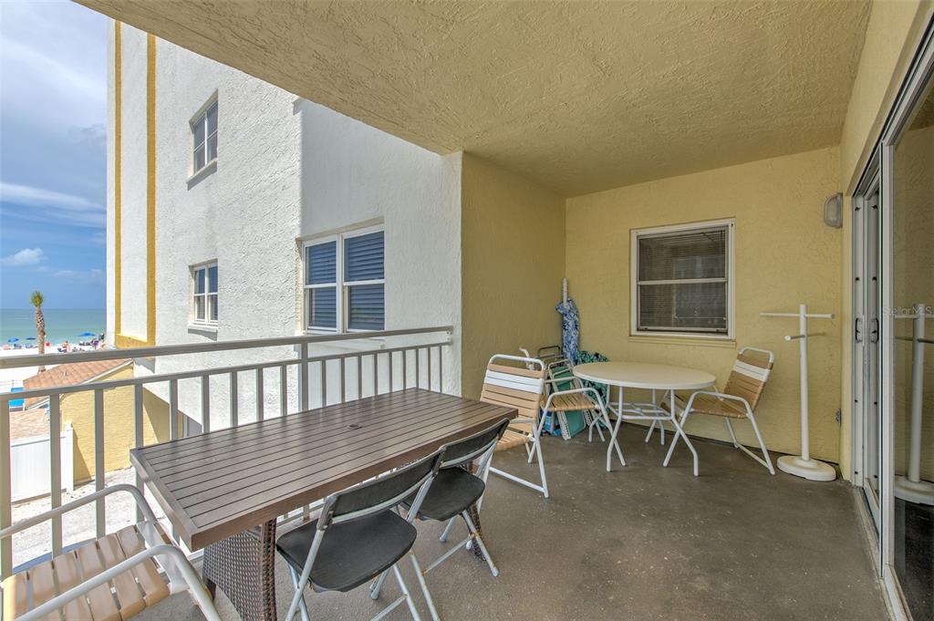 A covered balcony features a dining table, chairs, and a view of the beach — 17450 GULF BOULEVARD UNIT 103, REDINGTON SHORES, FL