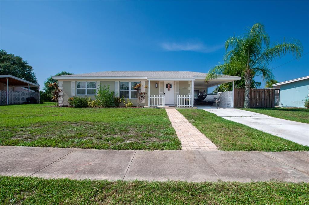 A single-story house with a light-colored exterior, a front walkway, and a carport — 22295 MONTROSE AVENUE, PORT CHARLOTTE, FL