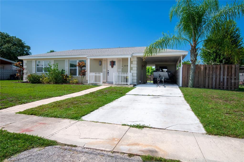 A single-story house with a white picket fence, a concrete driveway, and a carport — 22295 MONTROSE AVENUE, PORT CHARLOTTE, FL