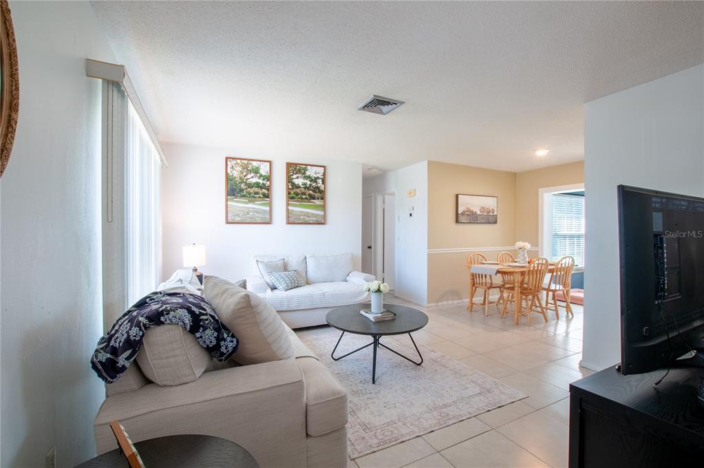 A living room and dining area with tile floors, neutral walls, and light-colored furniture — 22295 MONTROSE AVENUE, PORT CHARLOTTE, FL