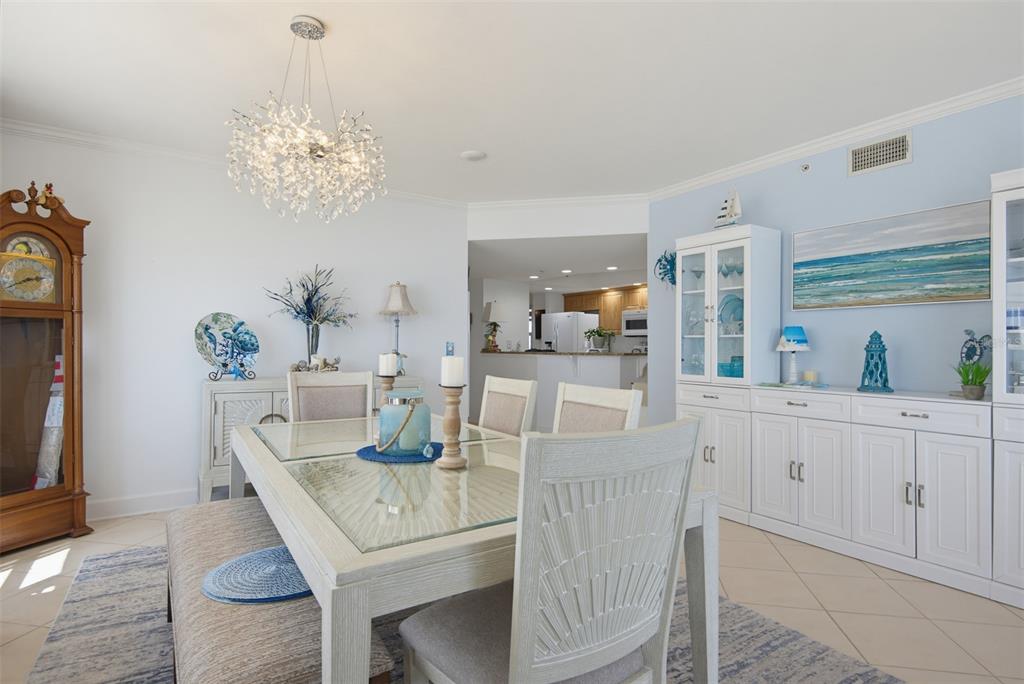 A dining room features a glass-topped table, a crystal chandelier, and a tall grandfather clock — 3315 S ATLANTIC AVENUE UNIT 408, DAYTONA BEACH SHORES, FL