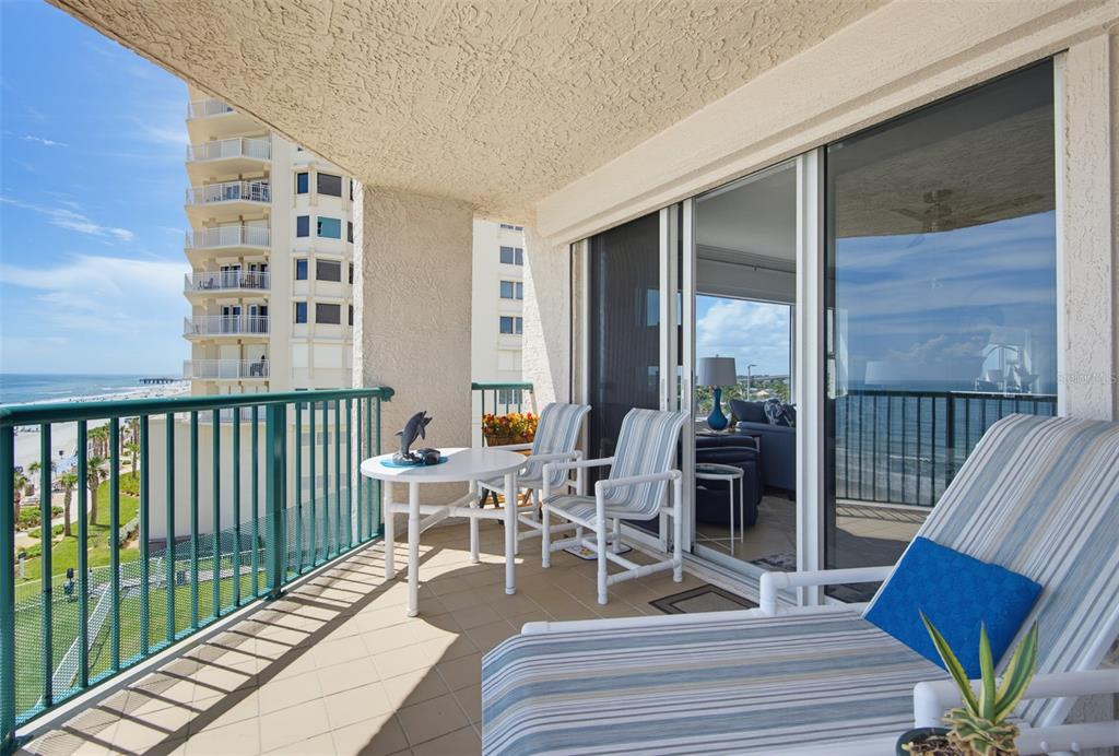 A balcony with patio furniture overlooks the ocean and a neighboring high-rise building — 3315 S ATLANTIC AVENUE UNIT 408, DAYTONA BEACH SHORES, FL