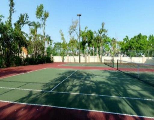 An outdoor tennis court with a green surface and a net under a clear sky — SUNRISE, FL