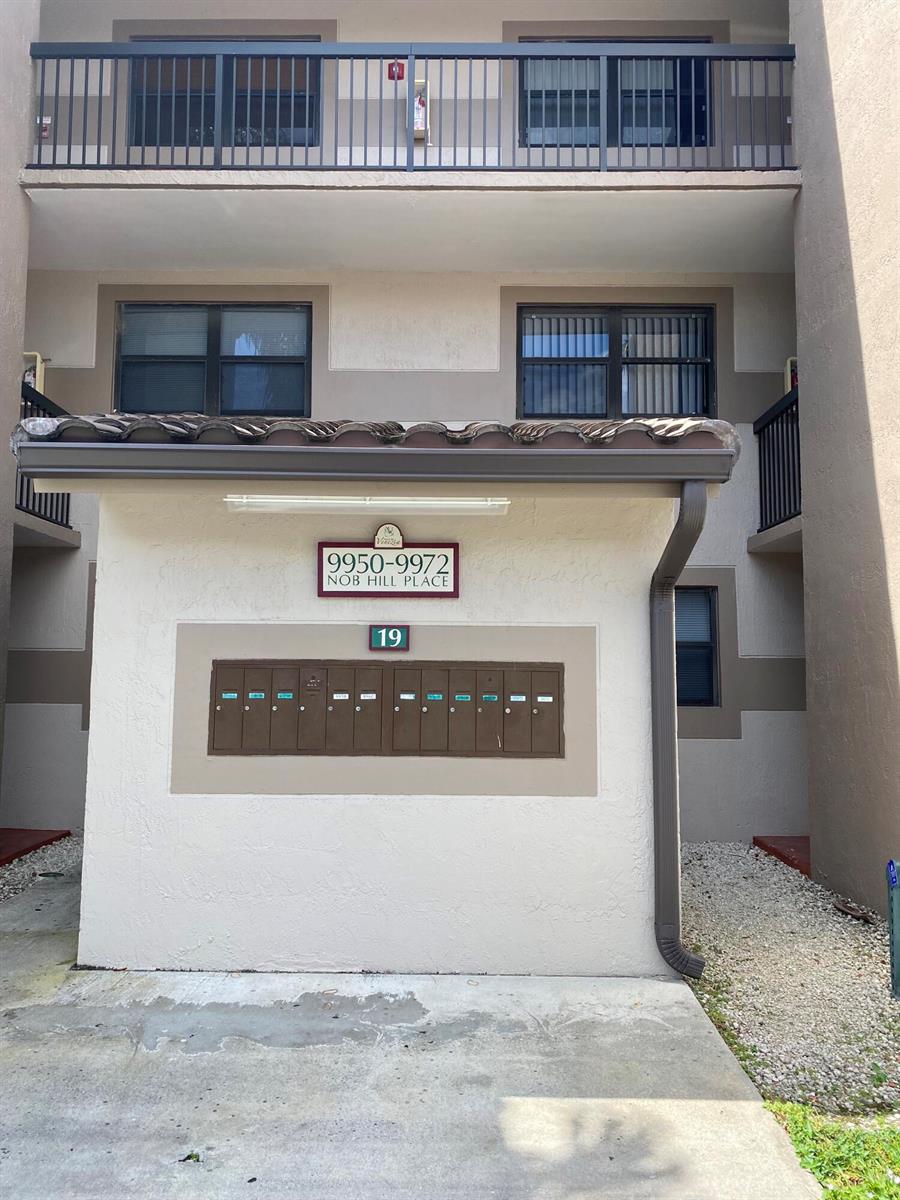 An exterior view of a building entrance featuring a cluster of mailboxes and balconies — SUNRISE, FL