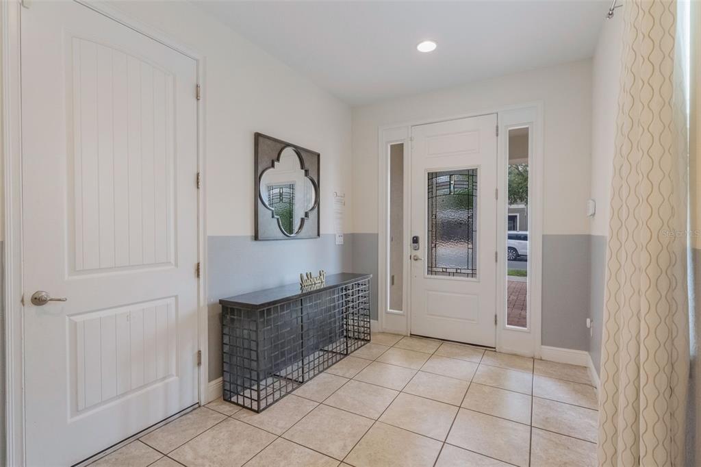An entryway features a tiled floor, a metal console table, a mirror, and a front door — 331 PENDANT COURT, KISSIMMEE, FL