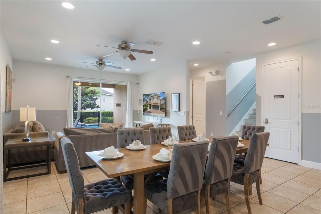 A dining area with a wooden table and chairs sits in front of a living room — 331 PENDANT COURT, KISSIMMEE, FL