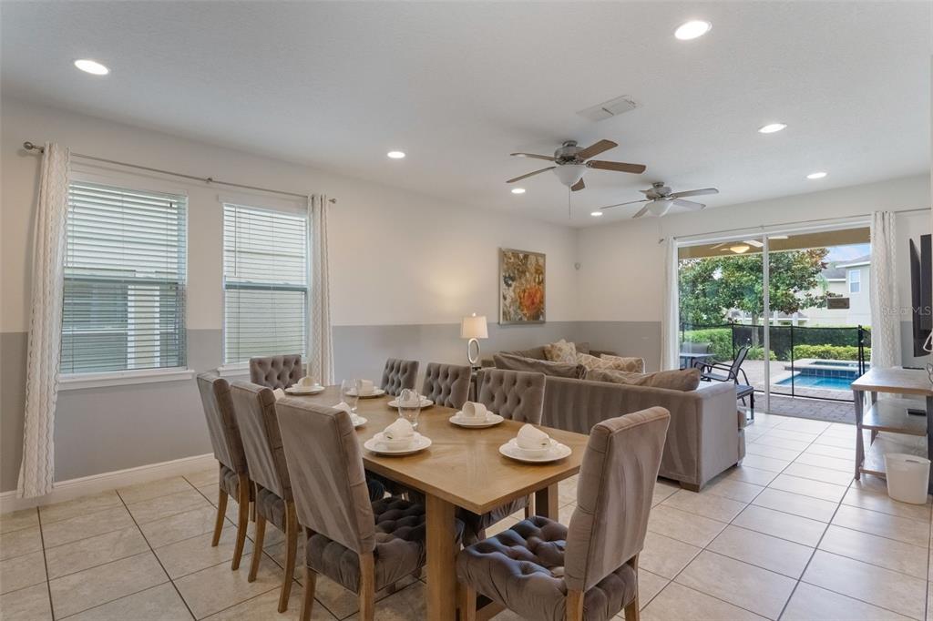 A dining area with a wooden table and tufted chairs opens to a living room — 331 PENDANT COURT, KISSIMMEE, FL