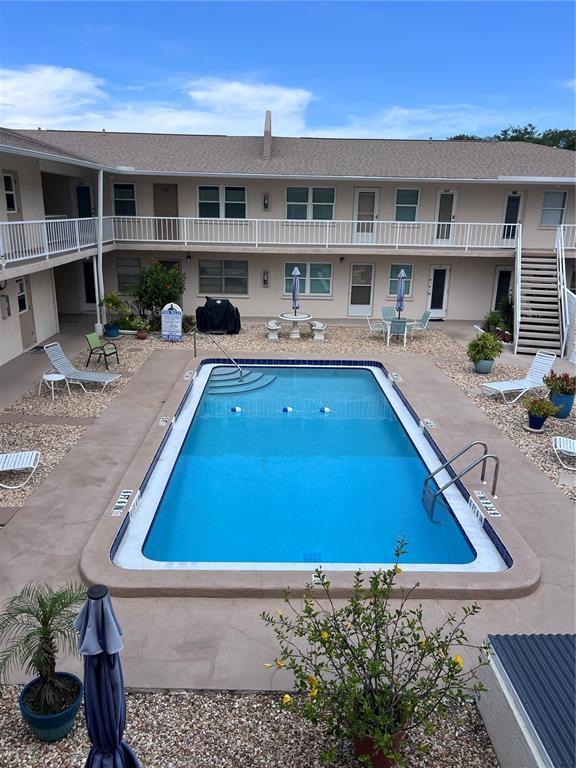 A rectangular swimming pool sits in a courtyard surrounded by a two-story apartment building — 509 W VENICE AVENUE UNIT 102, VENICE, FL