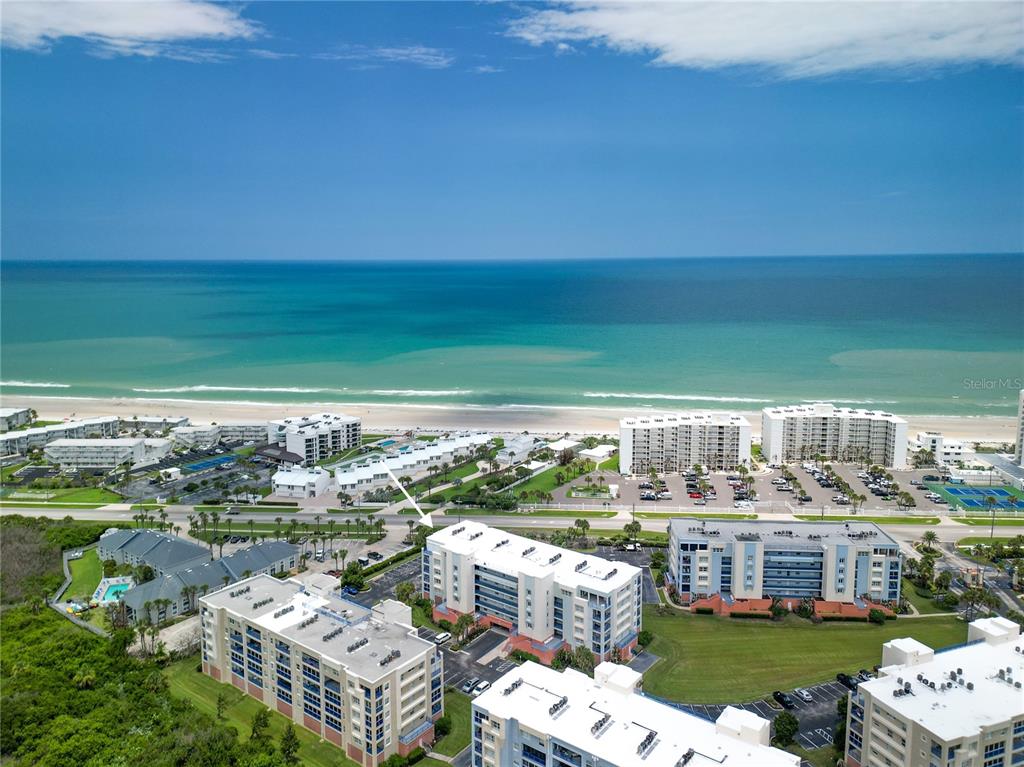 An aerial view shows several multi-story apartment buildings located near a sandy beach and ocean — 5300 S ATLANTIC AVENUE UNIT 3-302, NEW SMYRNA BEACH, FL