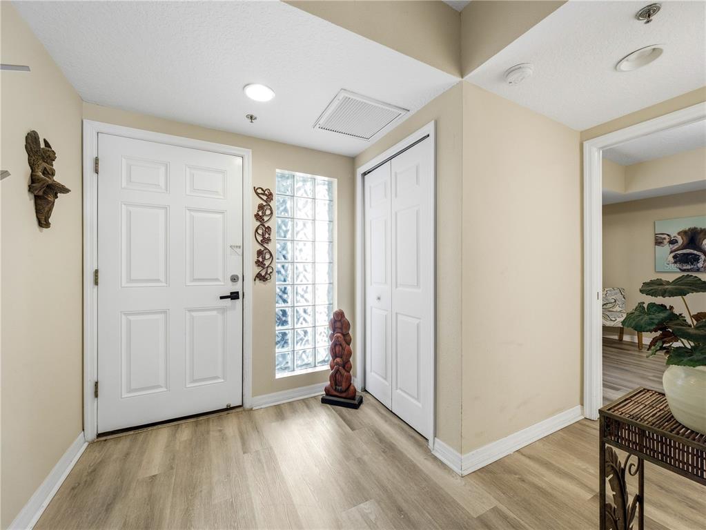 An entryway features light wood-look flooring, a white front door, and a glass block window — 5300 S ATLANTIC AVENUE UNIT 3-302, NEW SMYRNA BEACH, FL