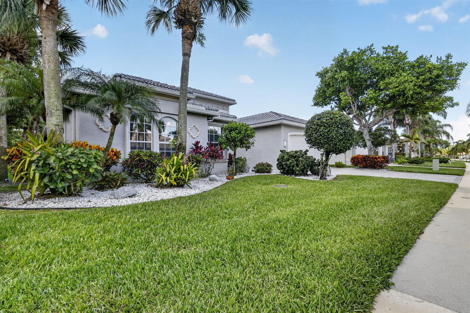 A single-story house with a gray stucco exterior, a tiled roof, and a landscaped front yard — 6550 Sand City Way, Delray Beach FL 33446, DELRAY BEACH, FL