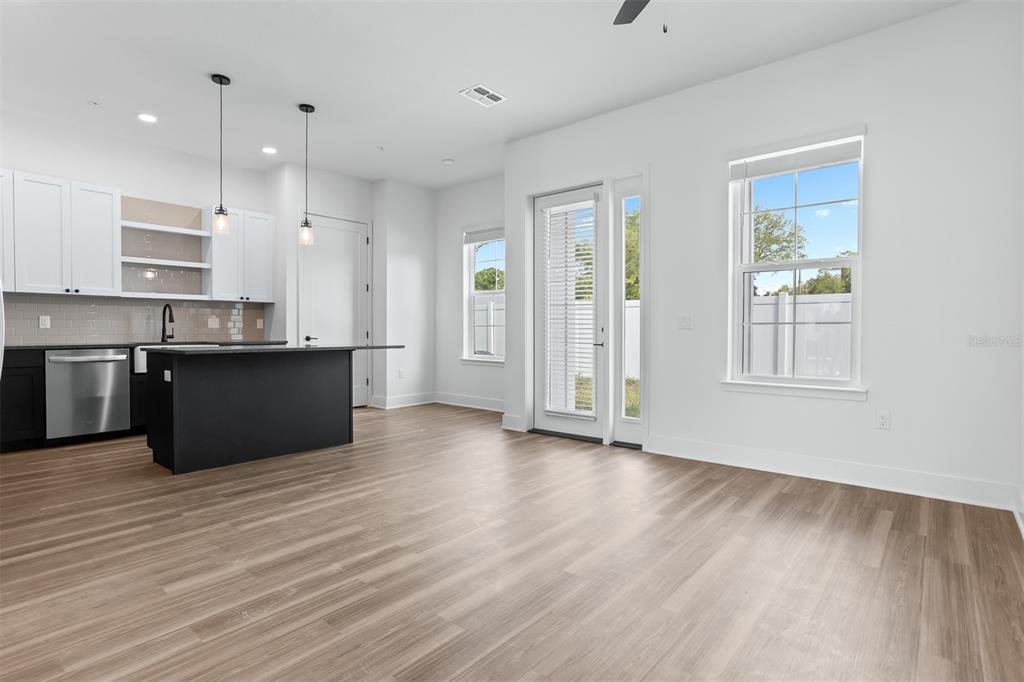 A kitchen with a black island and white cabinets opens into a bright living area — 3814 FERN HOLLOW PLACE, TAMPA, FL