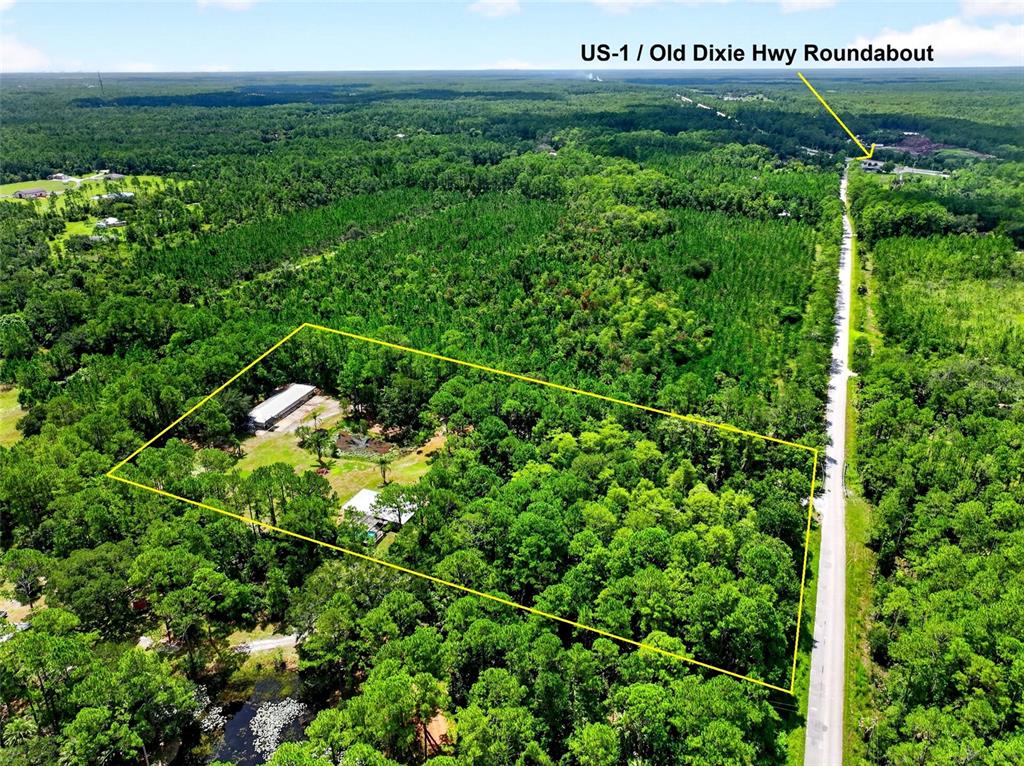 An aerial view shows a rectangular property with buildings surrounded by dense forest near a road — 590 COUNTY ROAD 325, BUNNELL, FL