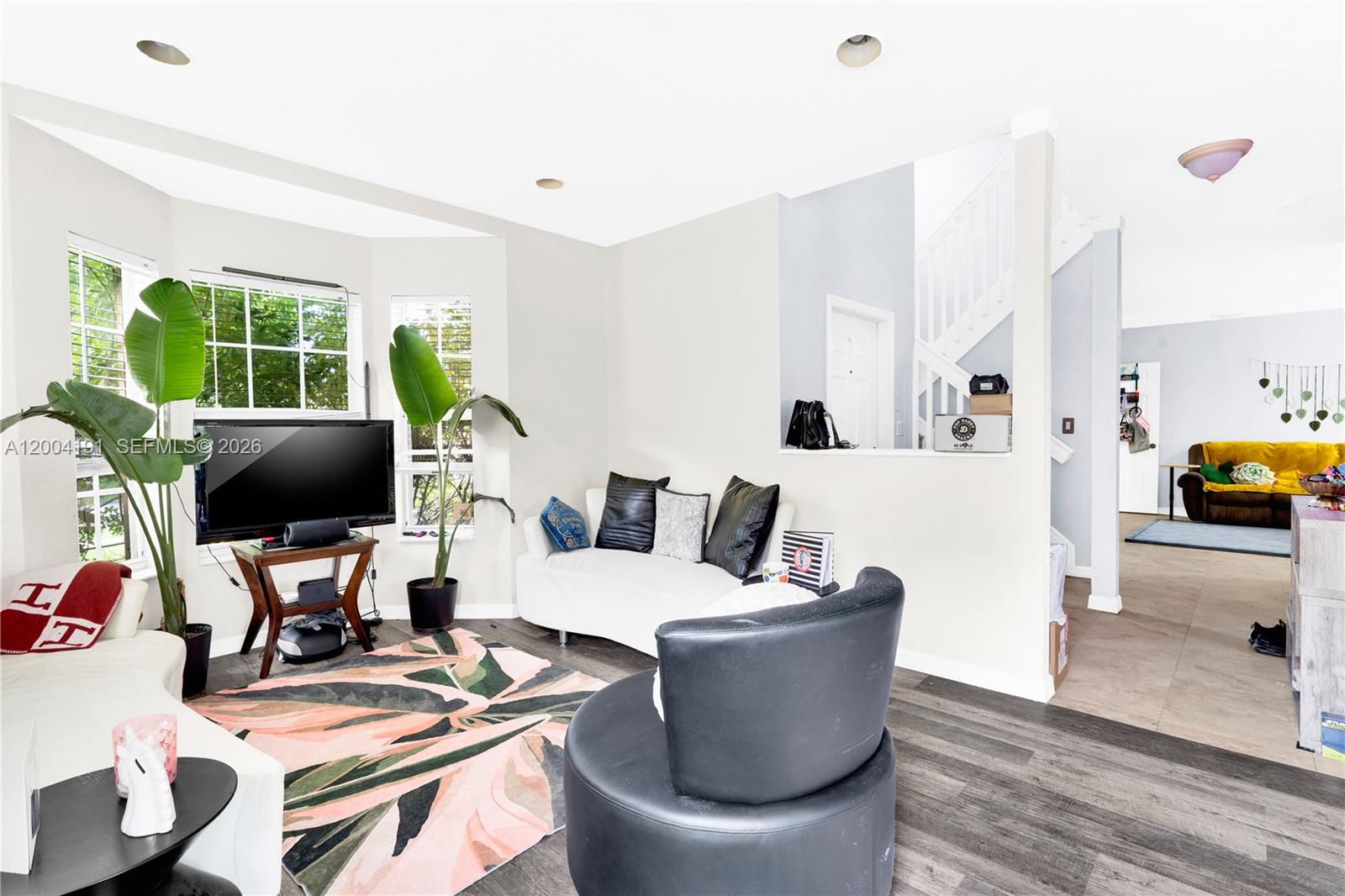 A living room features a curved white sofa, a black armchair, and a patterned area rug — 9031 SW 208th Ter, Cutler Bay FL 33189, CUTLER BAY, FL