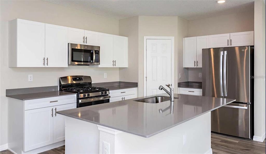 A kitchen with white cabinets, stainless steel appliances, and a gray quartz island countertop — 12935 HAWKSTONE TRAIL BOULEVARD, LITHIA, FL