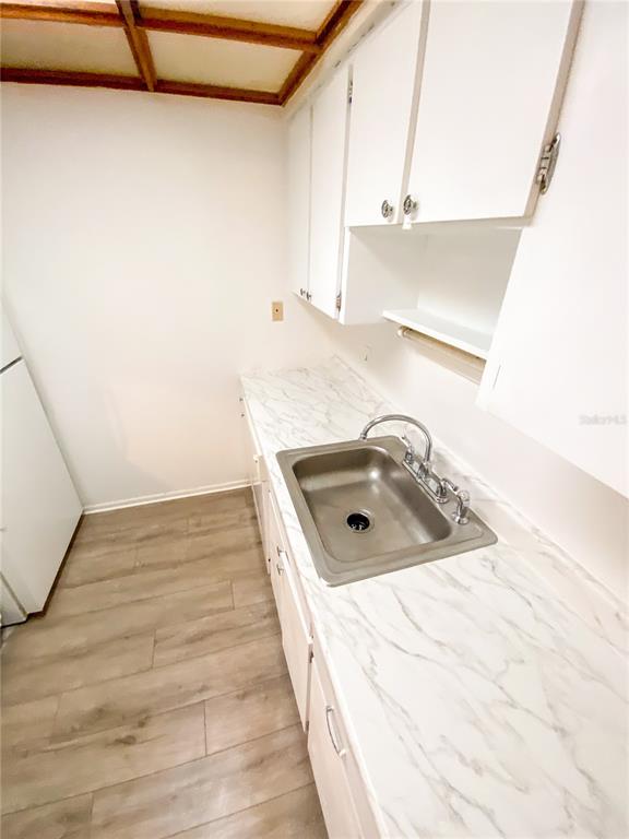 A kitchen features white cabinets, a stainless steel sink, and faux marble countertops — 4325 AEGEAN DRIVE UNIT 128B, TAMPA, FL