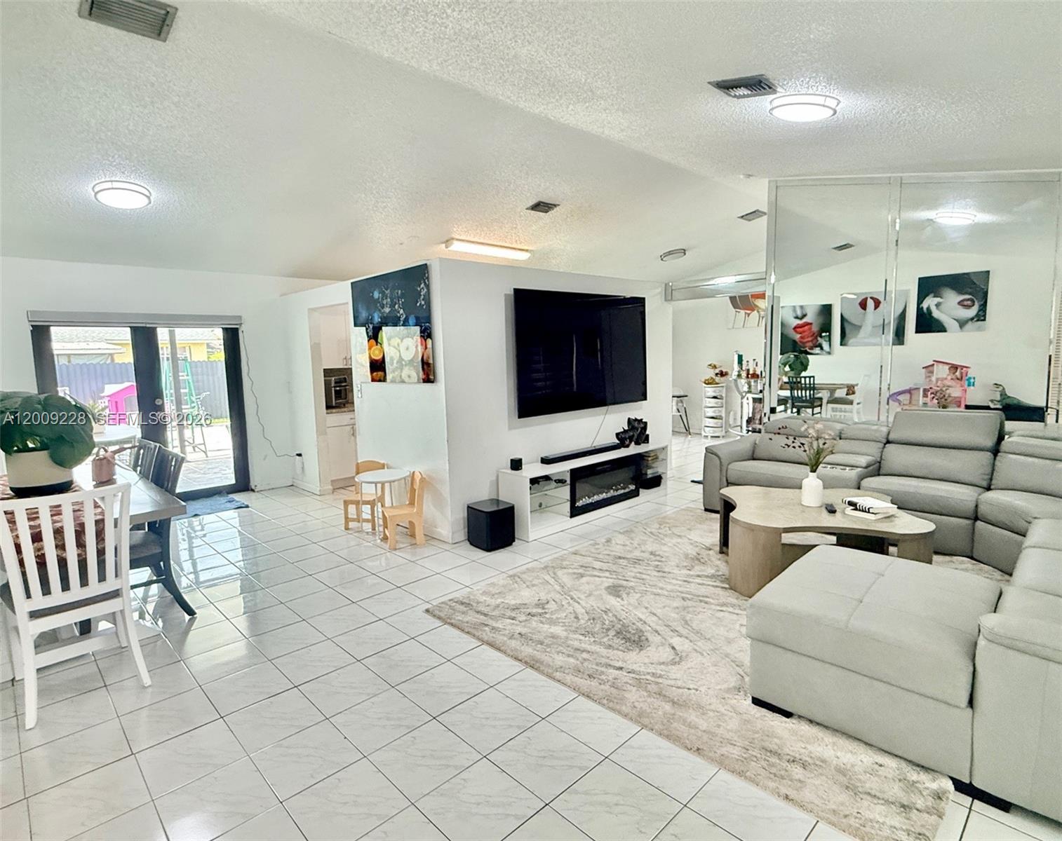 A living room with tile floors, a large sectional sofa, and a wall-mounted television — 11216 SW 166th Ter, Miami FL 33157, MIAMI, FL