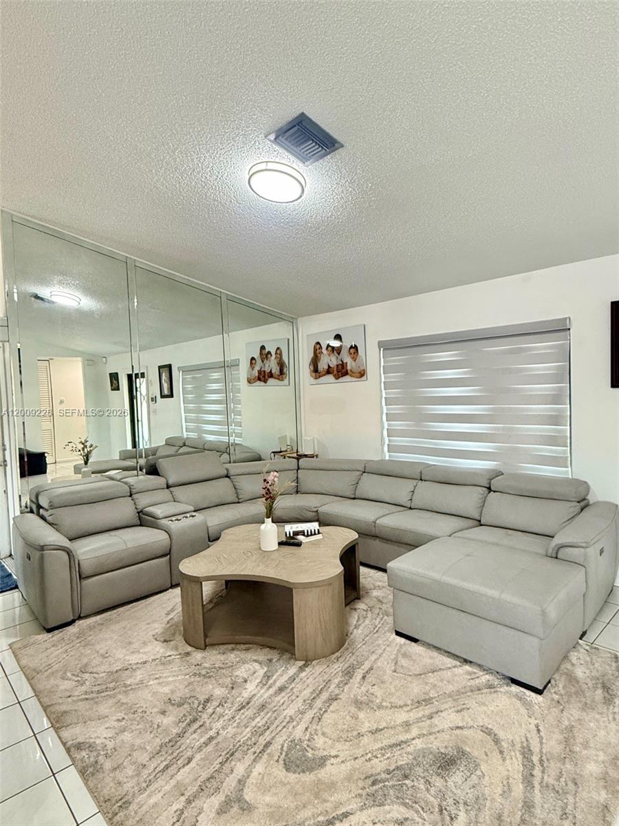 A living room features a large grey sectional sofa, a coffee table, and mirrored walls — 11216 SW 166th Ter, Miami FL 33157, MIAMI, FL